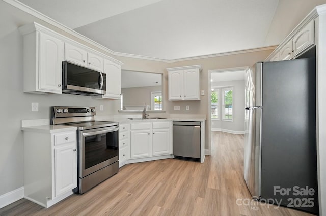kitchen with stainless steel appliances, a sink, light wood-type flooring, white cabinetry, and light countertops
