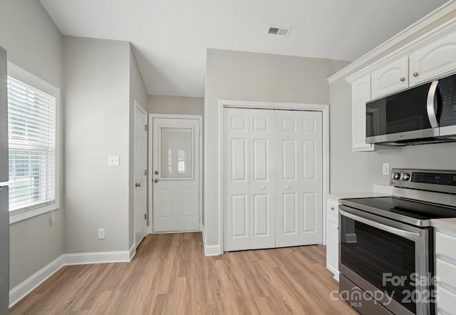8309 Emily Dr, Harrisburg, NC 28075 - kitchen featuring appliances with stainless steel finishes, light wood-type flooring, white cabinets, baseboards, and plenty of natural light