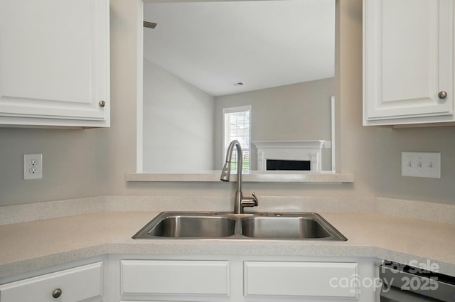 kitchen featuring a sink, white cabinets, a fireplace, dishwashing machine, and light countertops