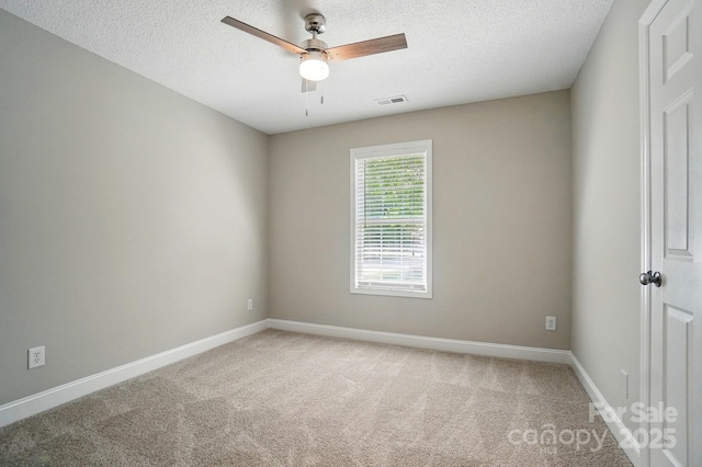 carpeted spare room with a ceiling fan, baseboards, and a textured ceiling