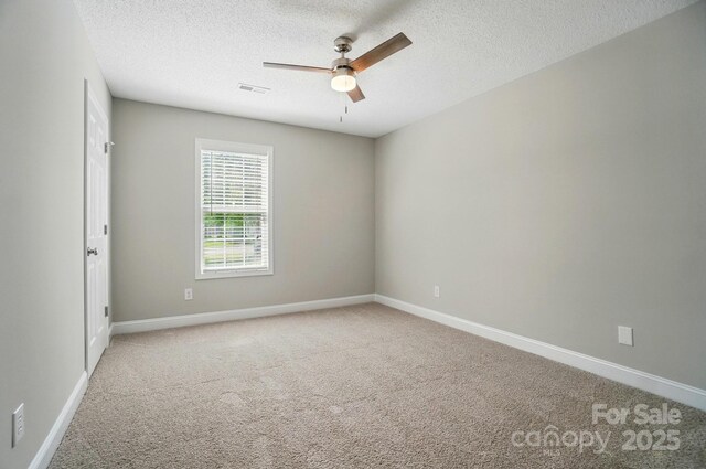 carpeted empty room featuring a ceiling fan, a textured ceiling, and baseboards