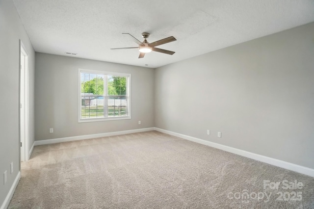 unfurnished room featuring ceiling fan, light carpet, a textured ceiling, and baseboards