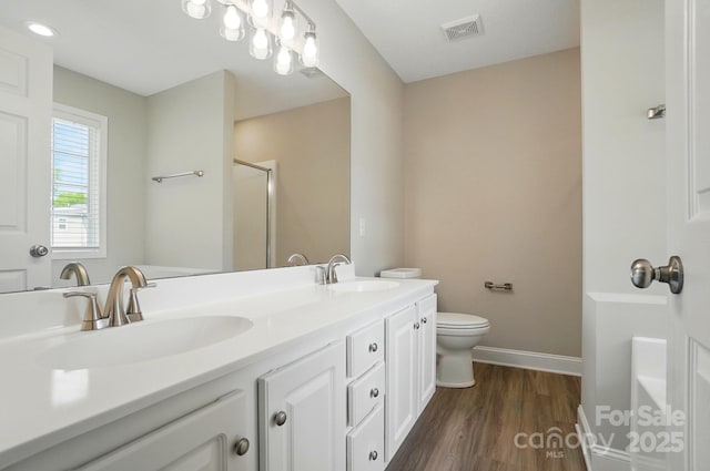 8309 Emily Dr, Harrisburg, NC 28075 - full bathroom featuring a shower with shower door, wood finished floors, double vanity, baseboards, and toilet