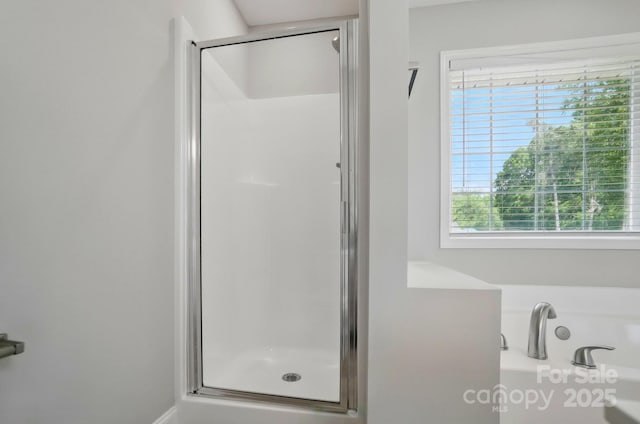 full bathroom with plenty of natural light, a shower stall, and a bath