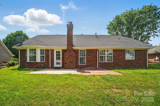 rear view of house with a patio, a chimney, a yard, and brick siding