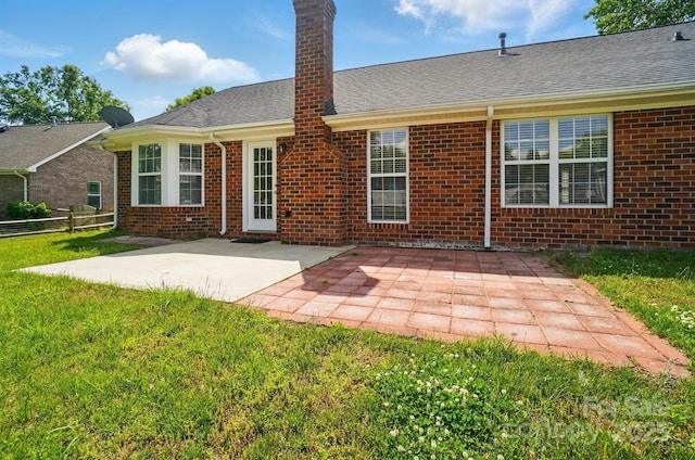 rear view of house featuring a patio area, brick siding, a chimney, and a shingled roof