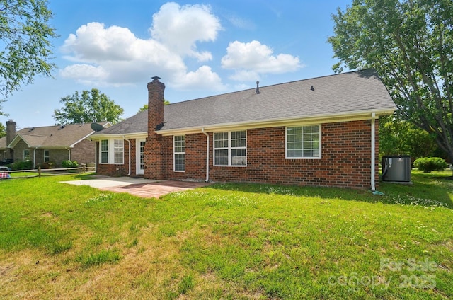 rear view of property with a patio area, cooling unit, brick siding, a yard, and a chimney