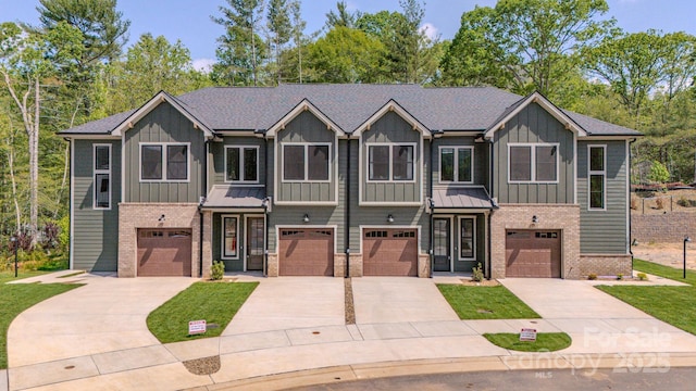 view of property featuring board and batten siding, brick siding, driveway, and a garage