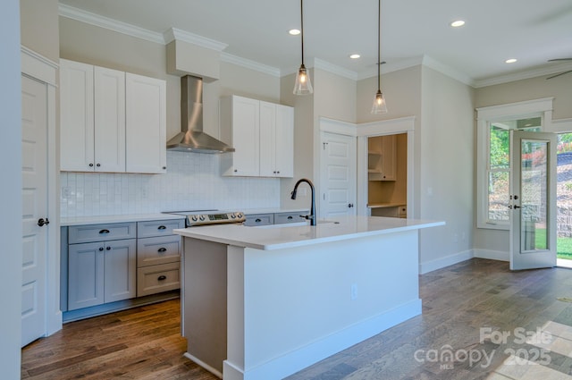 kitchen featuring recessed lighting, dark wood finished floors, wall chimney exhaust hood, backsplash, and light countertops
