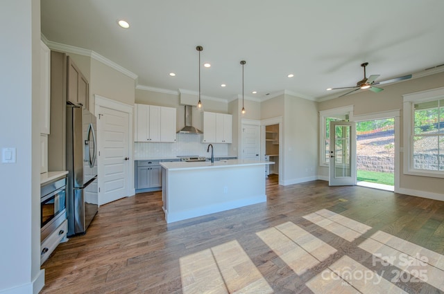 kitchen with ceiling fan, stainless steel fridge, wall chimney exhaust hood, wood finished floors, and tasteful backsplash