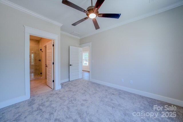unfurnished bedroom featuring ensuite bath, crown molding, ceiling fan, carpet flooring, and baseboards