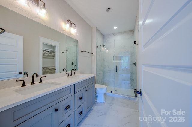 bathroom featuring a marble finish shower, marble finish floor, double vanity, and a sink