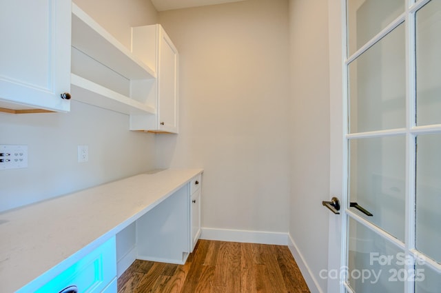 unfurnished office with baseboards and dark wood-type flooring