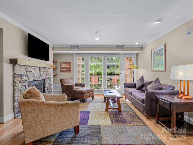 living room with a fireplace, crown molding, visible vents, and wood finished floors