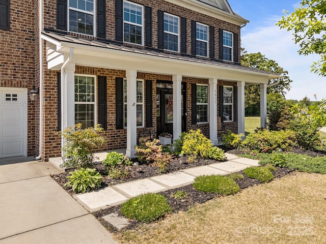 9871 Travertine Trl, Davidson, NC 28036 - doorway to property with covered porch, brick siding, and a garage
