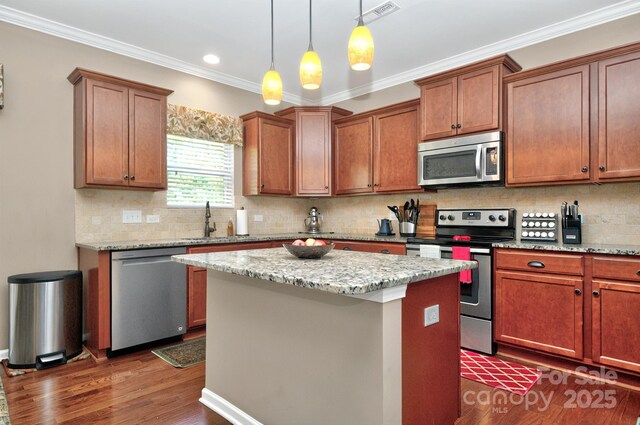 14837 Dungannon Ct, Charlotte, NC 28278 - kitchen with stainless steel appliances, dark wood-type flooring, a kitchen island, a sink, and ornamental molding