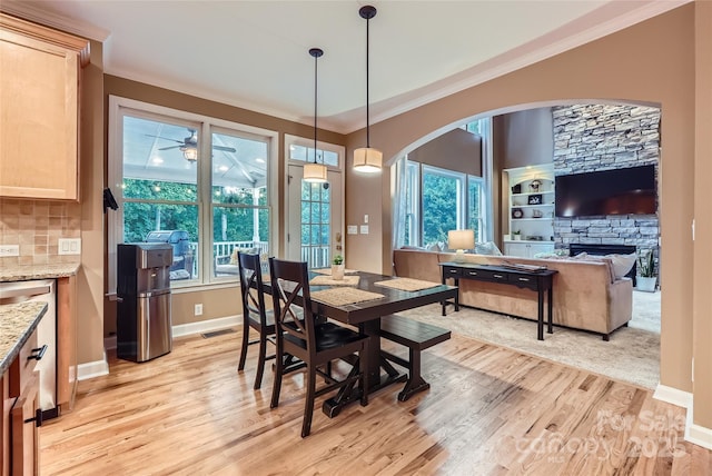 dining space with crown molding, arched walkways, light wood-type flooring, and visible vents