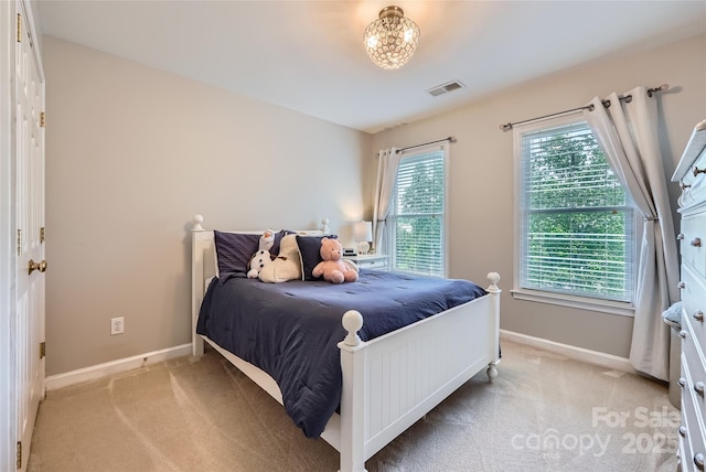 bedroom with light colored carpet, a chandelier, baseboards, and visible vents