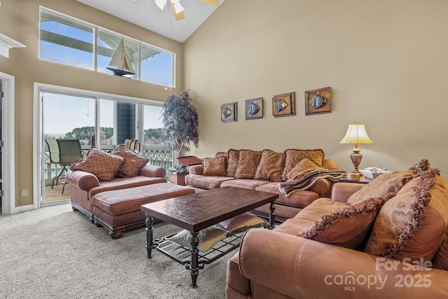 carpeted living area with a ceiling fan and high vaulted ceiling