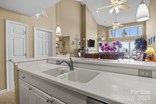 kitchen with hanging light fixtures, a ceiling fan, high vaulted ceiling, a sink, and light countertops