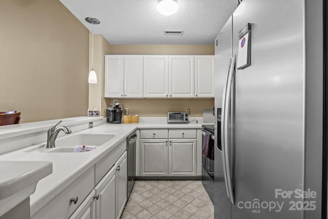 kitchen with a sink, stainless steel appliances, a textured ceiling, visible vents, and white cabinetry
