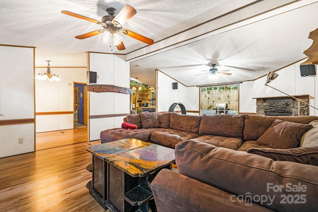 15 Robin Ln, Asheville, NC 28806 - living room featuring ceiling fan, a textured ceiling, light wood finished floors, a stone fireplace, and a chandelier