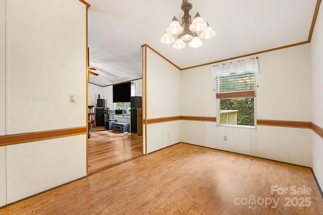 15 Robin Ln, Asheville, NC 28806 - empty room with a chandelier, wood finished floors, ornamental molding, vaulted ceiling, and a textured ceiling