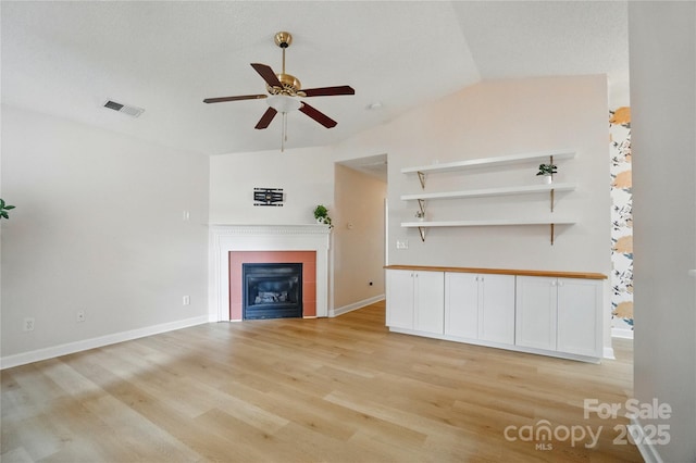 1162 Willet Dr, Rock Hill, SC 29732 - unfurnished living room featuring a ceiling fan, vaulted ceiling, light wood-style flooring, a glass covered fireplace, and baseboards