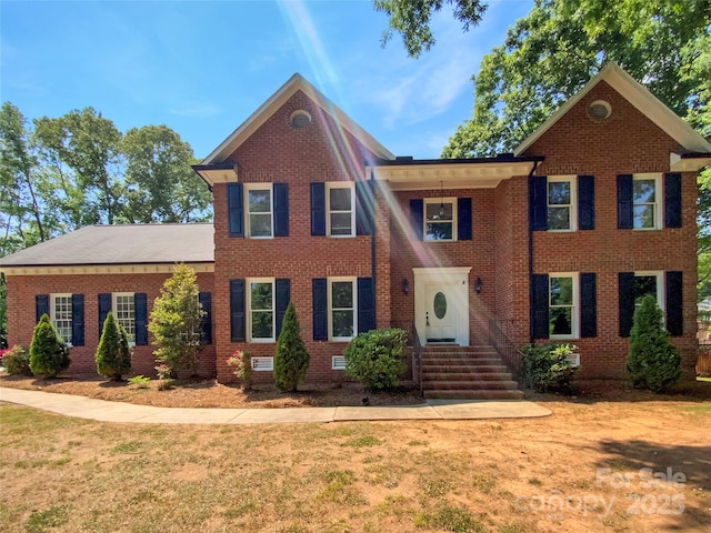 view of front facade with brick siding and a front lawn