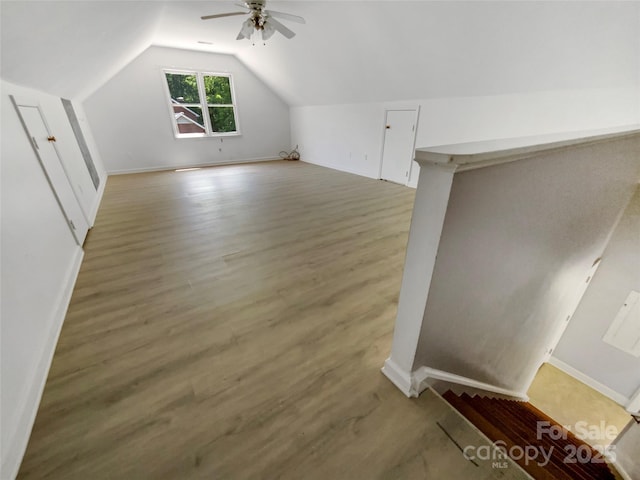 bonus room featuring vaulted ceiling, baseboards, a ceiling fan, and light wood-style floors
