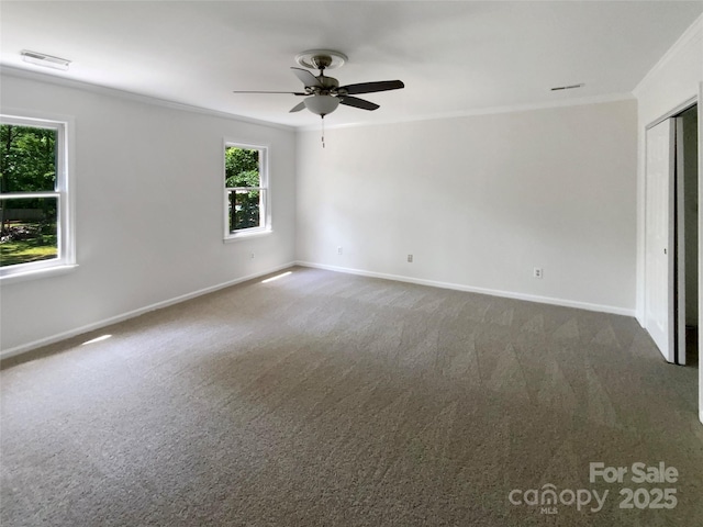 spare room with crown molding, baseboards, ceiling fan, and carpet floors