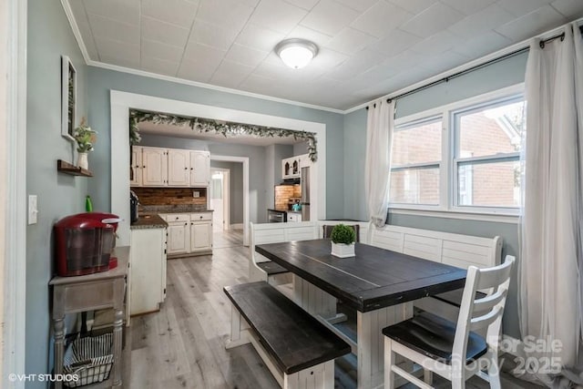 dining area with crown molding and light wood finished floors