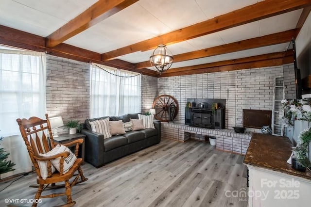 living area with a wealth of natural light, a wood stove, beam ceiling, and light wood-type flooring