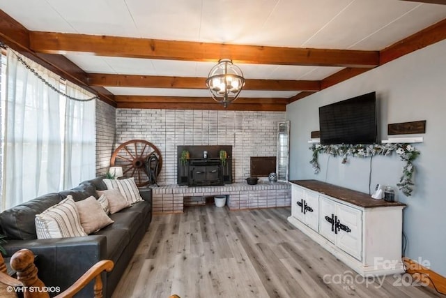 living area featuring beamed ceiling, a wood stove, and light wood finished floors