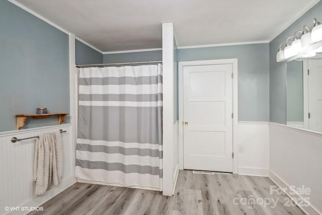 bathroom featuring crown molding, wood finished floors, wainscoting, and a shower with curtain