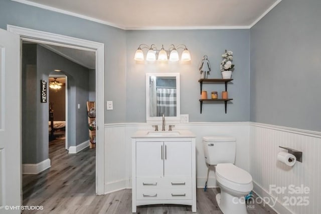 bathroom featuring vanity, toilet, wood finished floors, and wainscoting
