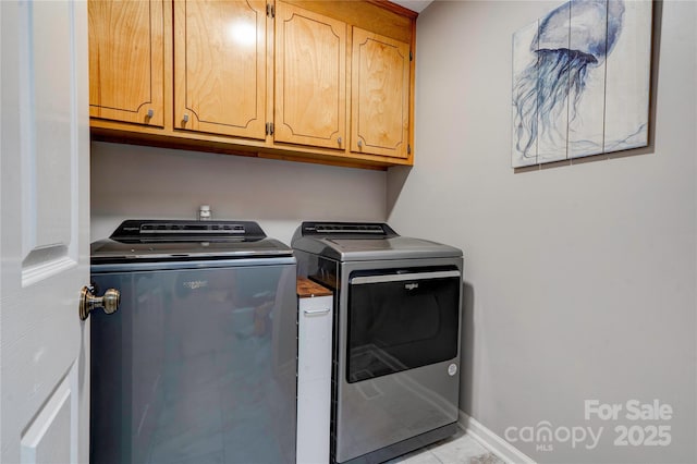 laundry area featuring baseboards, washing machine and dryer, and cabinet space