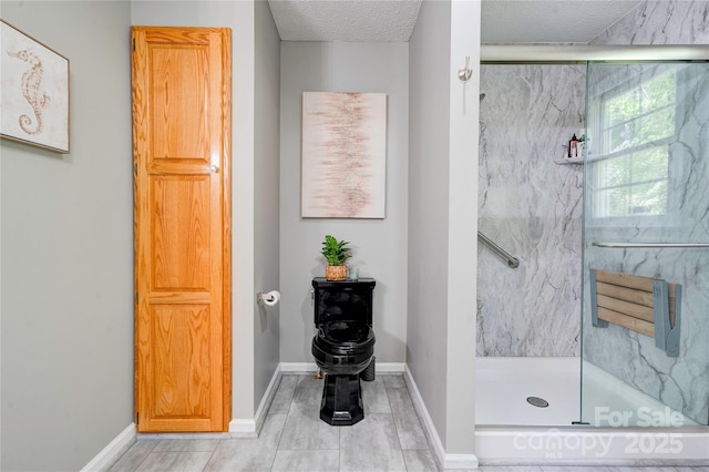 bathroom with a textured ceiling, a marble finish shower, and baseboards