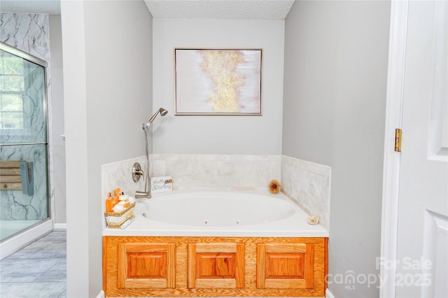 bathroom featuring a shower stall, baseboards, a jetted tub, and a textured ceiling