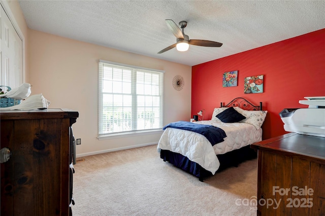 bedroom with a closet, a textured ceiling, baseboards, ceiling fan, and carpet floors
