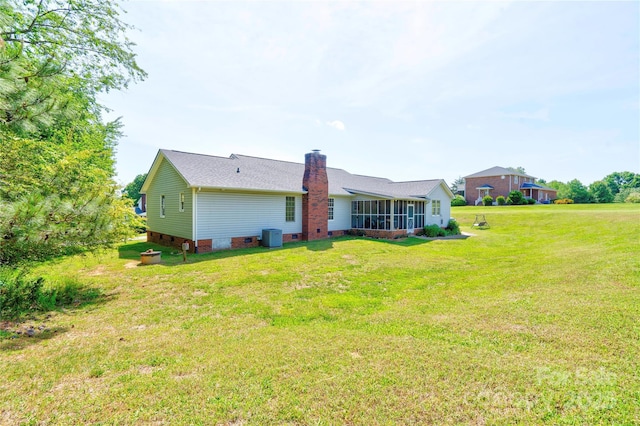 rear view of property with a chimney, a yard, a sunroom, crawl space, and central AC unit
