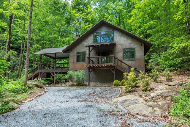 rear view of property featuring stairway, a deck, and a wooded view