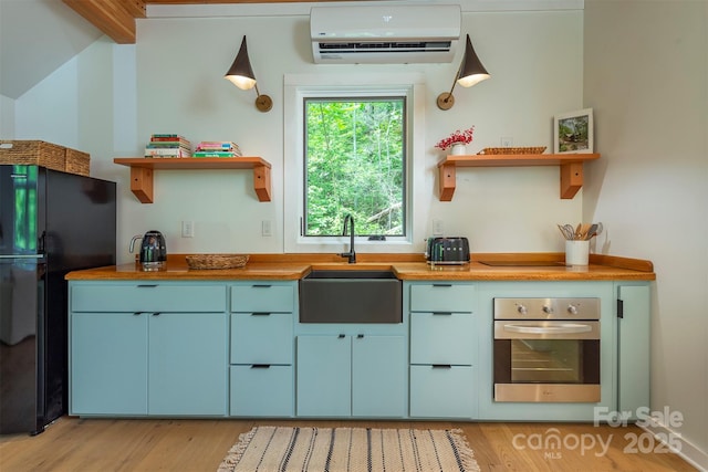 kitchen featuring stainless steel oven, open shelves, a wall mounted AC, and a sink