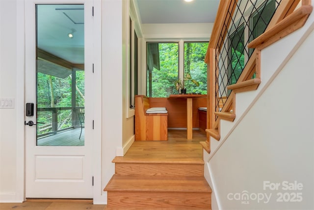 doorway to outside with stairs, wood finished floors, healthy amount of natural light, and baseboards