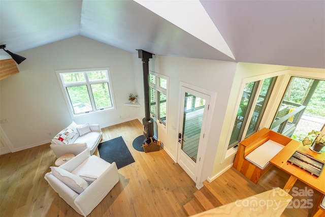 living area with lofted ceiling, light wood-type flooring, plenty of natural light, and baseboards