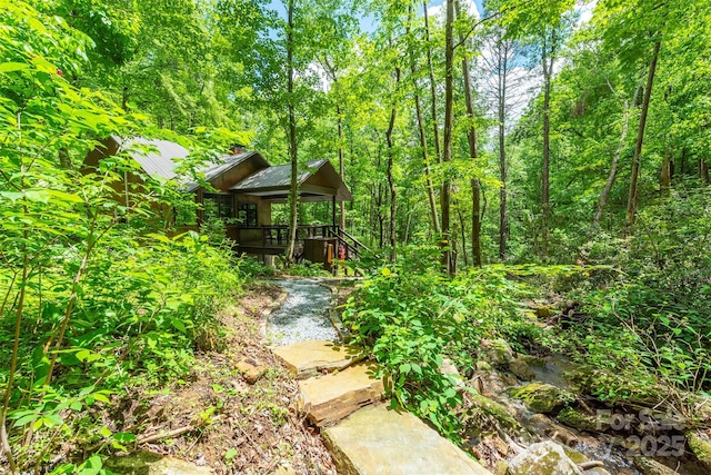 view of yard featuring a deck and a forest view