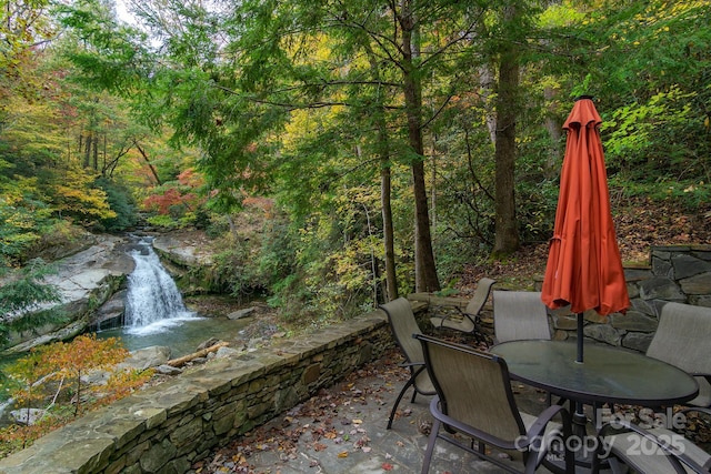 view of patio / terrace featuring a wooded view and outdoor dining area