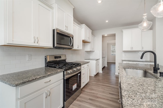 2021 Boynton St, Charlotte, NC 28269 - kitchen with appliances with stainless steel finishes, a sink, light stone countertops, light wood-style flooring, and recessed lighting