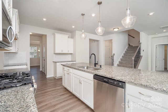 2021 Boynton St, Charlotte, NC 28269 - kitchen featuring stainless steel appliances, a sink, light wood-style flooring, decorative backsplash, and white cabinetry