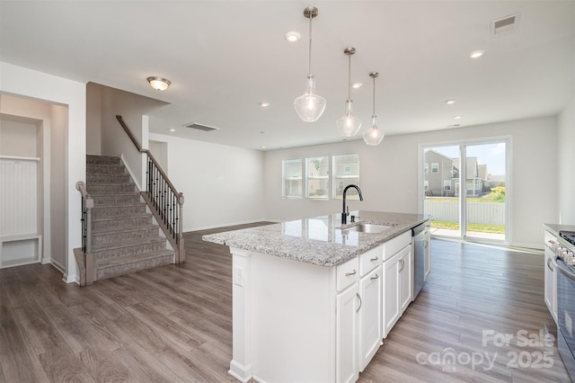 2021 Boynton St, Charlotte, NC 28269 - kitchen featuring a sink, light wood-type flooring, appliances with stainless steel finishes, white cabinetry, and light stone counters